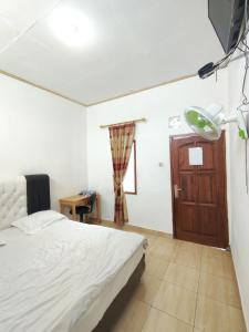 a bedroom with a bed and a wooden door at Penginapan Nurmega jaya in Lembursitu +36 photos