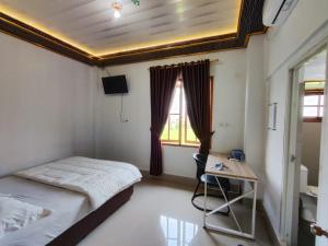a bedroom with a bed and a desk and a window at Penginapan Nurmega jaya in Lembursitu