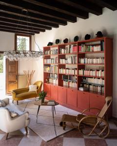 un salon avec une étagère rouge remplie de livres dans l'établissement Le 33, à Bassano del Grappa