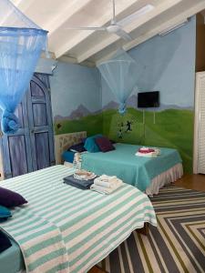 a bedroom with two beds and a painting on the wall at Aura Dominica in Roseau