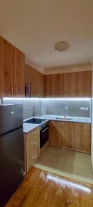 cocina con armarios de madera y nevera de acero inoxidable en Apartment in Sapphire Residence en Bansko
