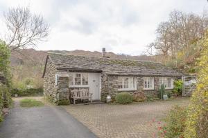 a stone cottage with a bench in front of it at Goody Bridge Barn in Grasmere