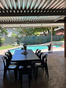 a dining table and chairs under a pergola next to a pool at Pompano Corner in Richards Bay