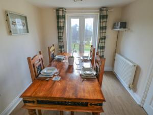 a wooden dining room table with chairs and plates on it at Saddlers Cottage, Berllandeg Farm in Clynderwen