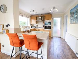 a kitchen with an island with orange chairs at Meadway House in Rhôs-on-Sea