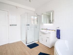 a white bathroom with a shower and a sink at Meadway House in Rhos-on-Sea