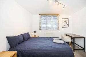 een slaapkamer met een blauw bed en een bureau bij Warm & Cosy Flat in King Cross in Londen
