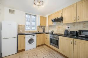 a kitchen with wooden cabinets and a washer and dryer at Warm & Cosy Flat in King Cross in London