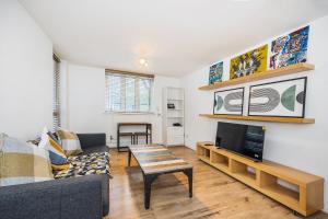 ein Wohnzimmer mit einem Sofa und einem TV in der Unterkunft Warm & Cosy Flat in King Cross in London