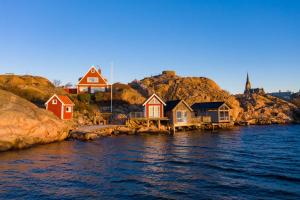 um grupo de casas na costa de uma massa de água em Strandflickornas Husen invid Havet em Lysekil