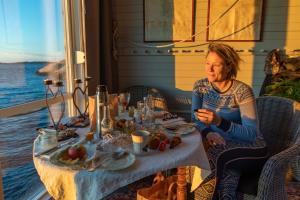 a woman sitting at a table with a plate of food at Strandflickornas Husen invid Havet in Lysekil