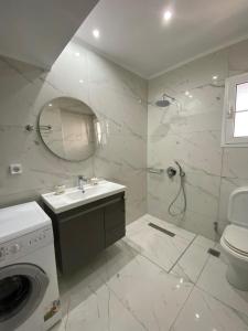 a bathroom with a sink and a washing machine at Lefkada Blue - Apartments in Lefkada Town