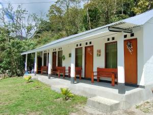 un pequeño edificio blanco con bancos en un patio en Rago's Homestay, en Kelimutu