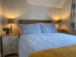 a bedroom with a bed with blue sheets and two lamps at 3 Bed in Wighton KT085 in Wighton