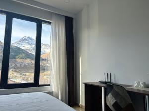 a bedroom with a large window with a mountain view at Shushabandi Kazbegi in Stepantsminda