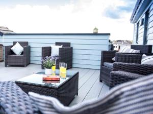 een patio met stoelen en een tafel met 2 glazen sinaasappelsap bij 3 Bed in Westward Ho 64410 in Northam