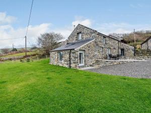 a stone house with a green lawn in front of it at 3 Bed in Aberdovey 75025 in Llwyngwril