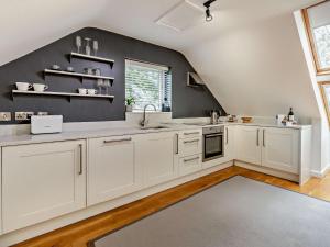 una cucina con armadietti bianchi e una parete nera di 1 Bed in Shrewsbury 73521 a Ford