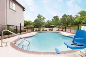 a swimming pool with a blue chair at Super 8 by Wyndham Huntsville in Huntsville