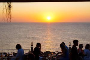 a group of people sitting around a table watching the sunset at Hostal La Torre Ibiza Cap Negret in San Antonio