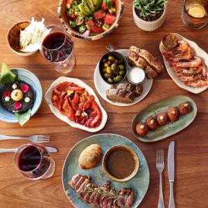 a wooden table with plates of food and glasses of wine at Hostal La Torre Ibiza Cap Negret in San Antonio