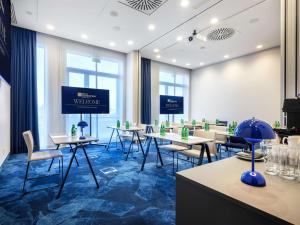 une salle de conférence avec des tables, des chaises et un écran dans l'établissement Hilton Garden Inn Krakow Airport, à Cracovie