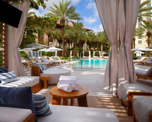 un patio del hotel con piscina, mesas y sillas en Hilton West Palm Beach, en West Palm Beach