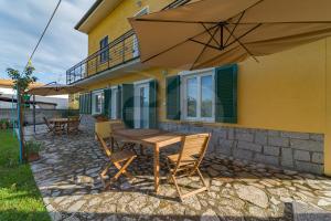 une terrasse avec une table et des chaises en bois ainsi qu'un parasol dans l'établissement Residence gli Olmi - Goelba, à Marina di Campo