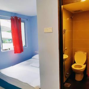 baño con cama, aseo y ventana en RAS Hotel en Kuala Lumpur