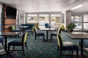 a waiting room with tables and chairs andwindows at Wingate by Wyndham Cedar City in Cedar City