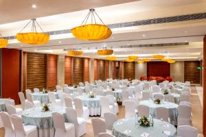a banquet hall with white tables and chairs and chandeliers at Sterling Puri in Puri