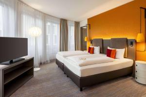 a hotel room with two beds and a flat screen tv at Sunday Hotel Leipzig in Leipzig +54 photos