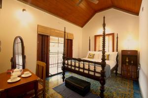 a bedroom with a bed and a desk and a table at The Mundanad House in Trivandrum