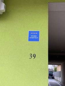 a green wall with a blue sign on it at Studio apartman Aurora in Đakovo