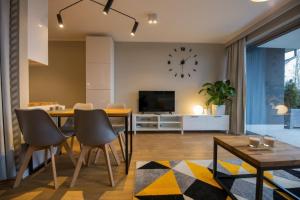 a living room with a table and a clock on the wall at VacationClub – Bukowa 17A Apartament E.2 in Wisła