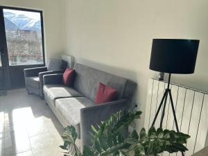 a living room with a gray couch with red pillows at Shushabandi Kazbegi in Kazbegi