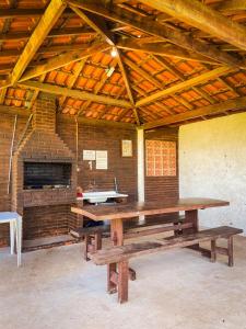 een grote houten tafel in een kamer met een bakstenen muur bij Lindo apto com lazer completo em Aguas de Lindoia in Águas de Lindóia