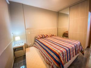 ein kleines Schlafzimmer mit einem Bett und einem Spiegel in der Unterkunft Lindo apto com lazer completo em Aguas de Lindoia in Águas de Lindóia