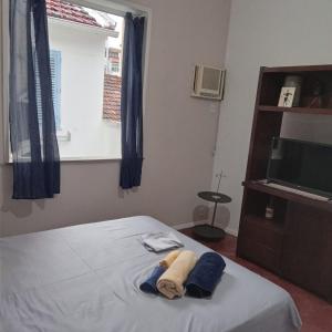 1 dormitorio con 1 cama con toallas y TV en Apartamento Barão da Torre, en Río de Janeiro