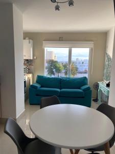 Una sala de estar con un sofá azul y una mesa. en J-H- DEPARTAMENTO, en Monte Hermoso