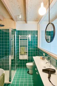 Baño de azulejos verdes con aseo y lavamanos en EvaMaria, en Varsenare