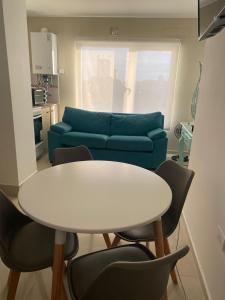 Una sala de estar con una mesa y un sofá azul. en J-H- DEPARTAMENTO, en Monte Hermoso