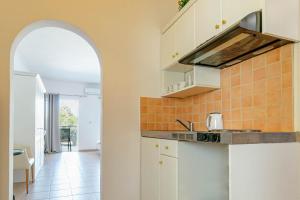 a kitchen with white cabinets and an archway at Porto Marina Aparthotel in Gouvia