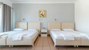 two beds in a room with white walls at Porto Marina Aparthotel in Gouvia