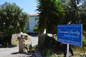 un panneau devant une maison avec un palmier dans l'établissement Troumpas Family Rooms & Apartments, à Leonidio