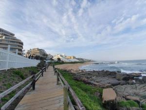 a wooden boardwalk leading to a beach with buildings at Spacious Seaview Apartment, 62 Perissa in Ballito