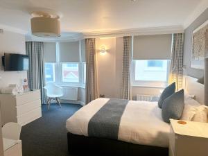 a hotel room with a bed and a desk and window at Legends Hotel in Brighton & Hove