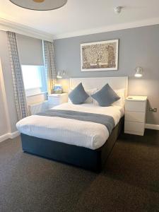 a bedroom with a large bed with blue pillows at Legends Hotel in Brighton & Hove