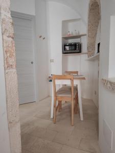 a table and chair in a kitchen with a microwave at Archi Antichi in Putignano
