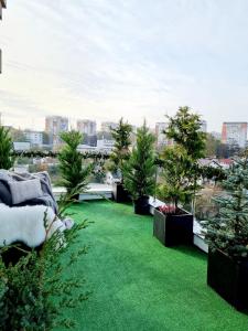 einen Hof mit grünem Gras und Bäumen auf einem Balkon in der Unterkunft Penthouse View Aeroport Iasi in Iaşi